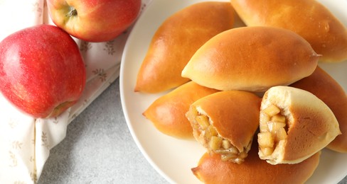 Photo of Tasty baked patties with apples on light grey table, flat lay
