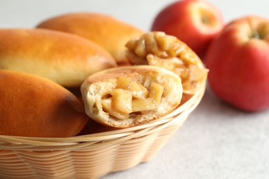 Photo of Tasty baked patties in wicker basket on light grey table, closeup