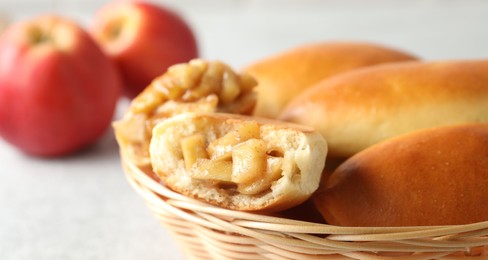 Photo of Tasty baked patties in wicker basket on light grey table, closeup