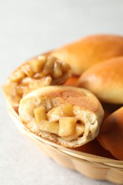 Photo of Tasty baked patties in wicker basket on light grey table, closeup