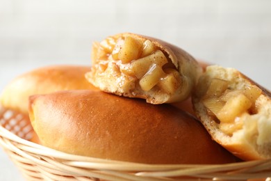 Photo of Tasty baked patties in wicker basket on blurred background, closeup