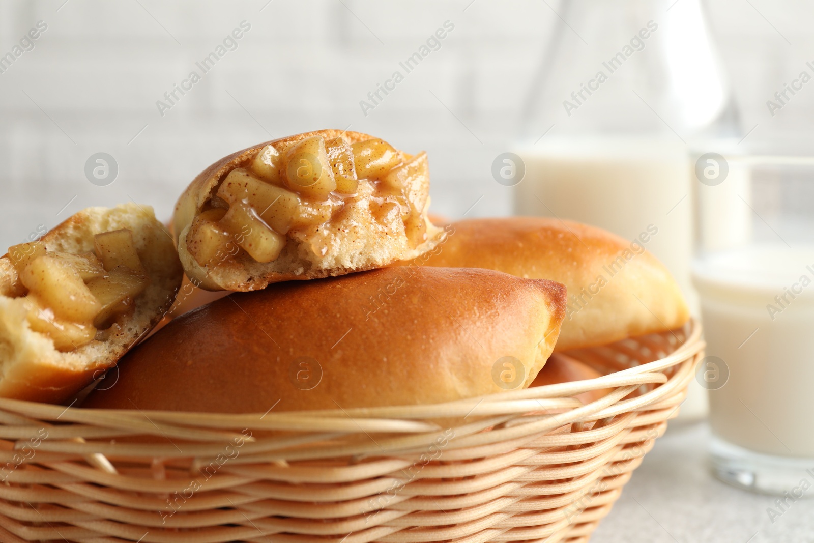 Tasty baked patties in wicker basket on light grey table, closeup Photo of Tasty baked patties in wicker basket on light grey table, closeup