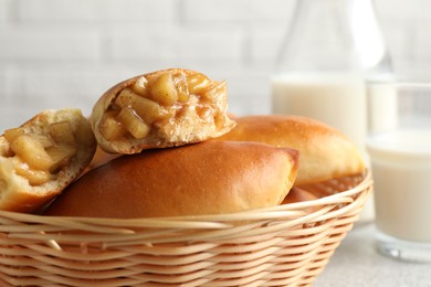 Photo of Tasty baked patties in wicker basket on light grey table, closeup