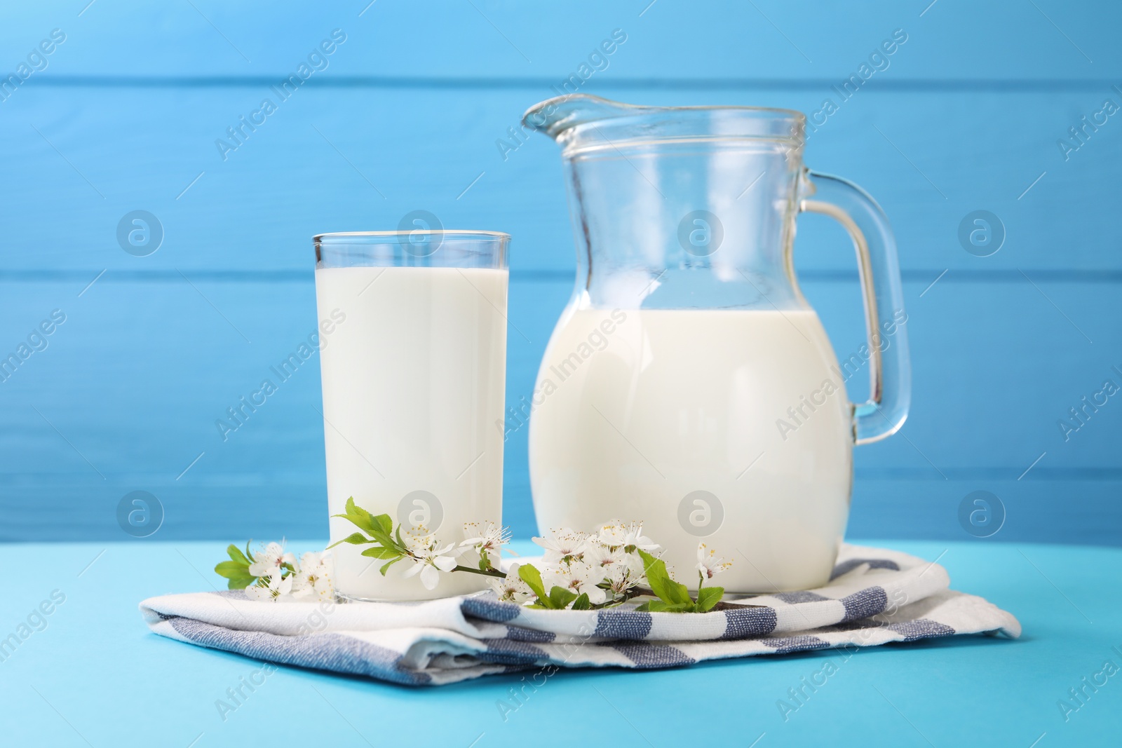 Fresh milk and blossoms on light blue table, closeup Photo of Fresh milk and blossoms on light blue table, closeup