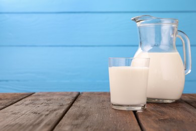 Photo of Fresh milk on wooden table against light blue background, closeup. Space for text