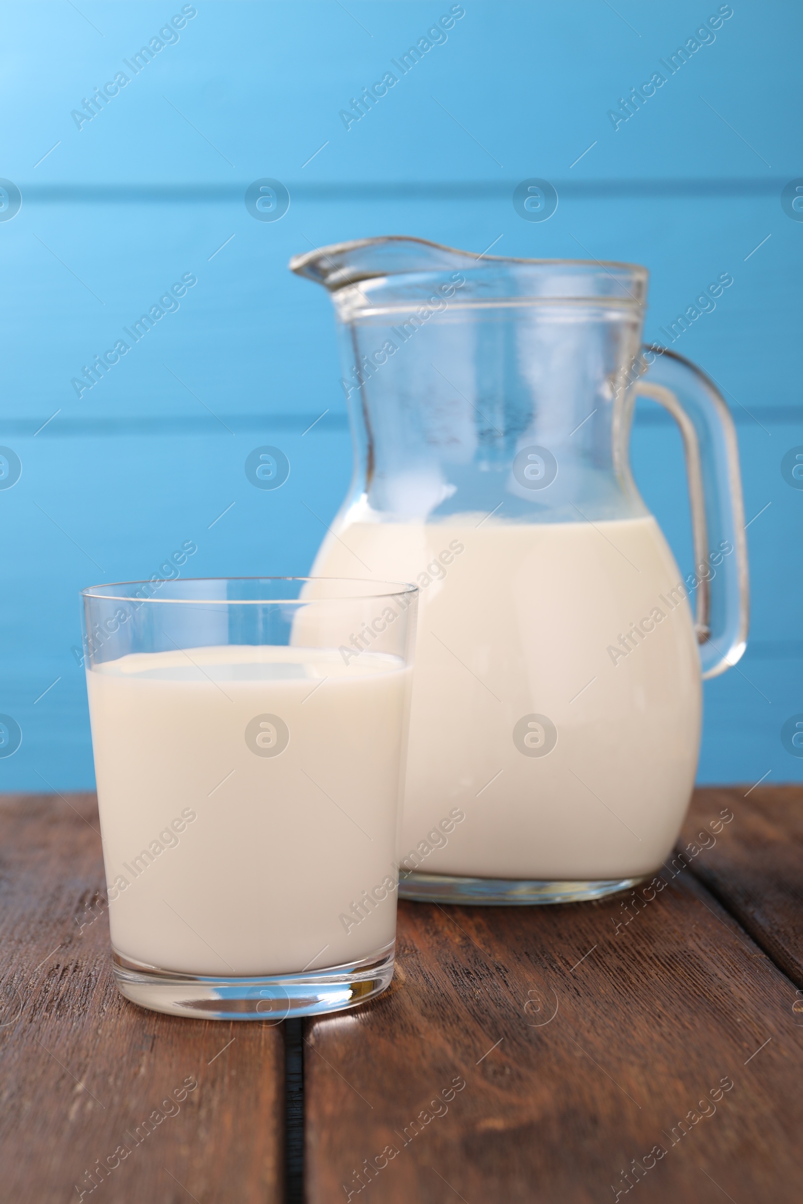 Fresh milk on wooden table against light blue background, closeup Photo of Fresh milk on wooden table against light blue background, closeup