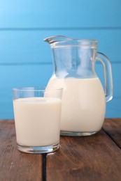 Photo of Fresh milk on wooden table against light blue background, closeup