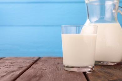 Photo of Fresh milk on wooden table against light blue background, closeup. Space for text