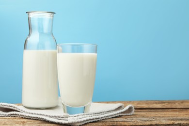 Photo of Fresh milk on wooden table against light blue background, closeup. Space for text