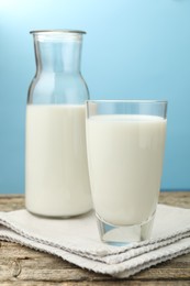 Photo of Fresh milk on wooden table against light blue background, closeup