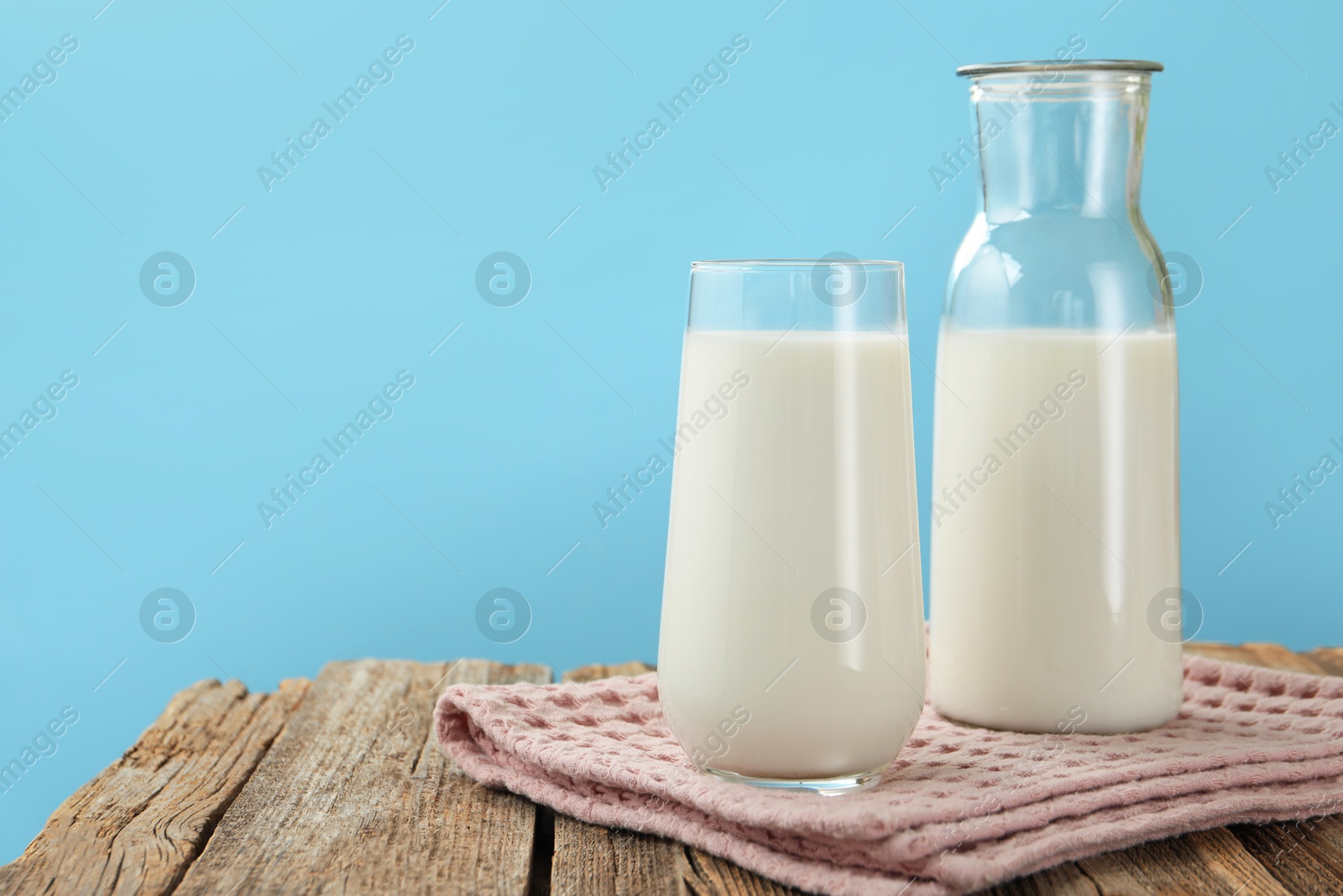 Fresh milk on wooden table against light blue background, closeup. Space for text Photo of Fresh milk on wooden table against light blue background, closeup. Space for text