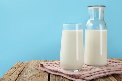 Photo of Fresh milk on wooden table against light blue background, closeup. Space for text