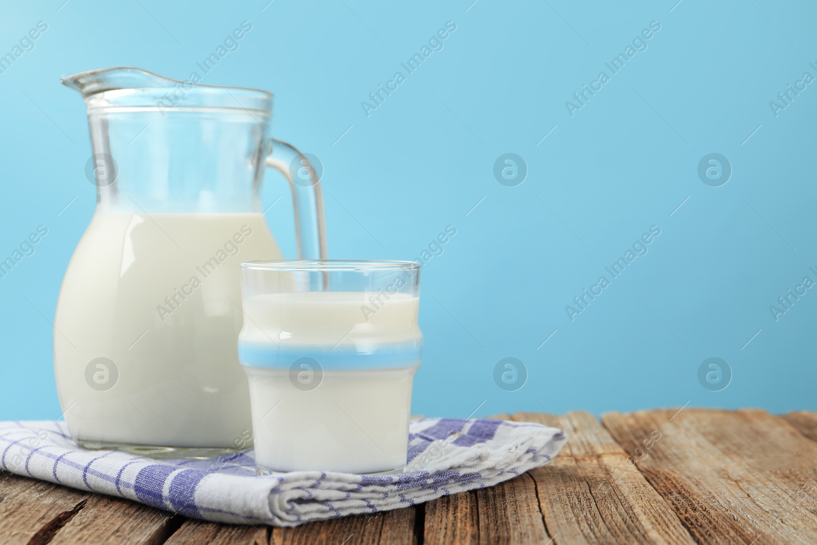 Fresh milk on wooden table against light blue background, closeup. Space for text Photo of Fresh milk on wooden table against light blue background, closeup. Space for text