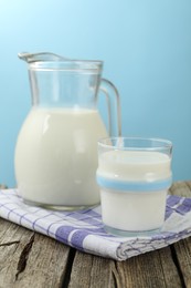 Photo of Fresh milk on wooden table against light blue background, closeup