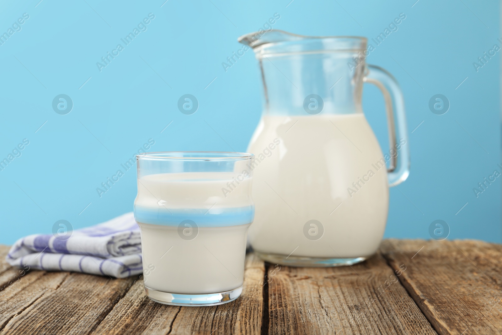 Fresh milk on wooden table against light blue background, closeup Photo of Fresh milk on wooden table against light blue background, closeup
