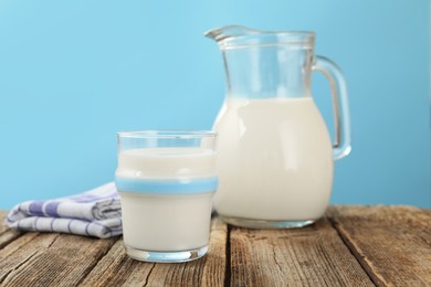Photo of Fresh milk on wooden table against light blue background, closeup
