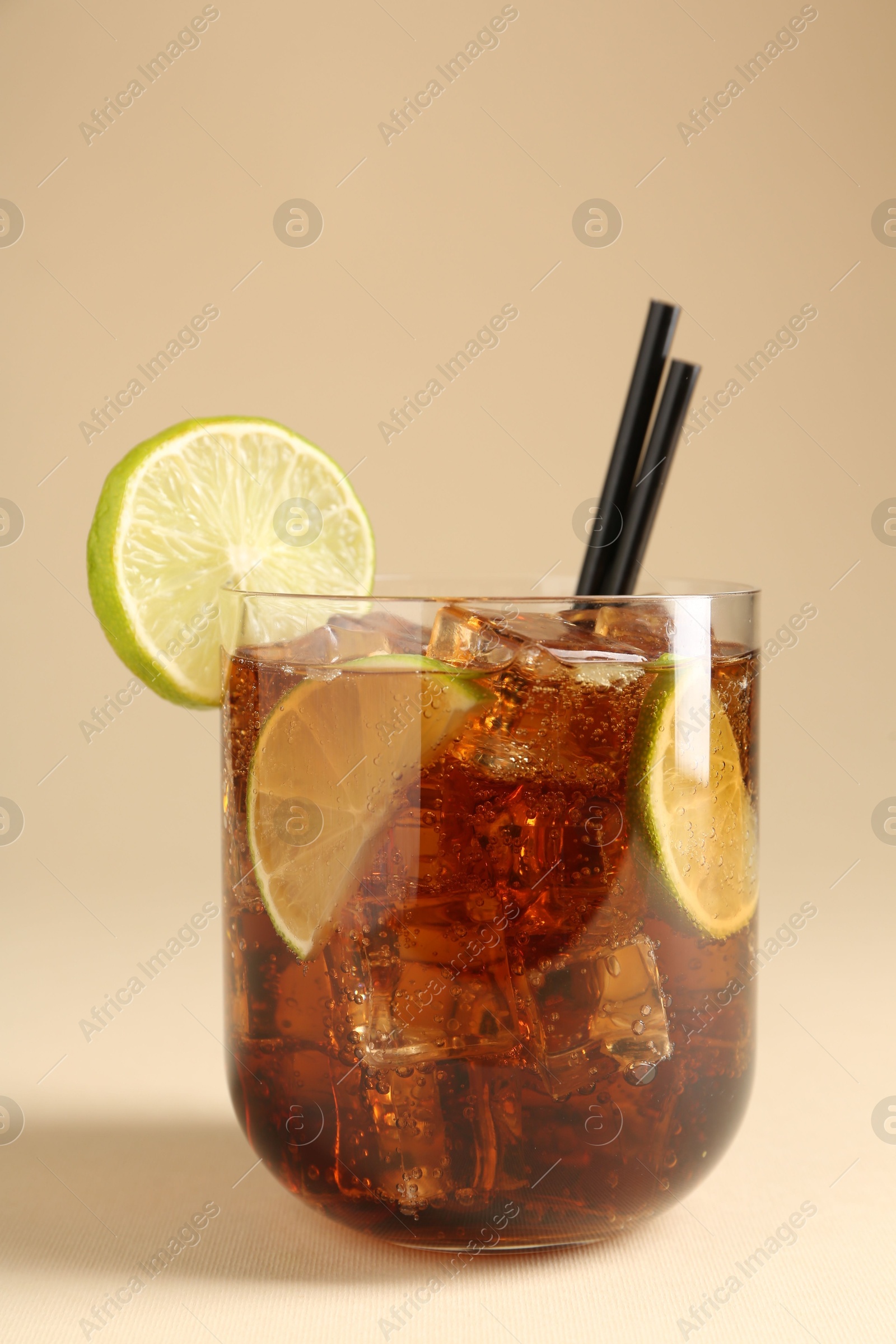 Tasty Cuba Libre cocktail in glass on beige background Photo of Tasty Cuba Libre cocktail in glass on beige background