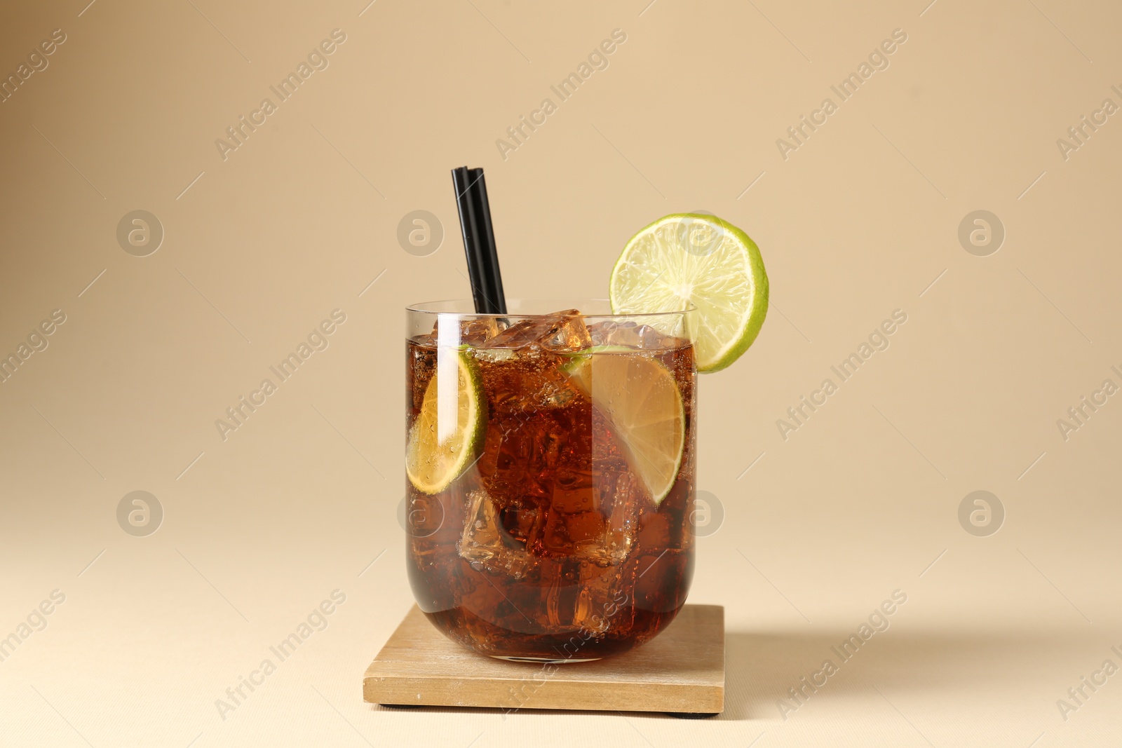 Tasty Cuba Libre cocktail in glass on beige background Photo of Tasty Cuba Libre cocktail in glass on beige background