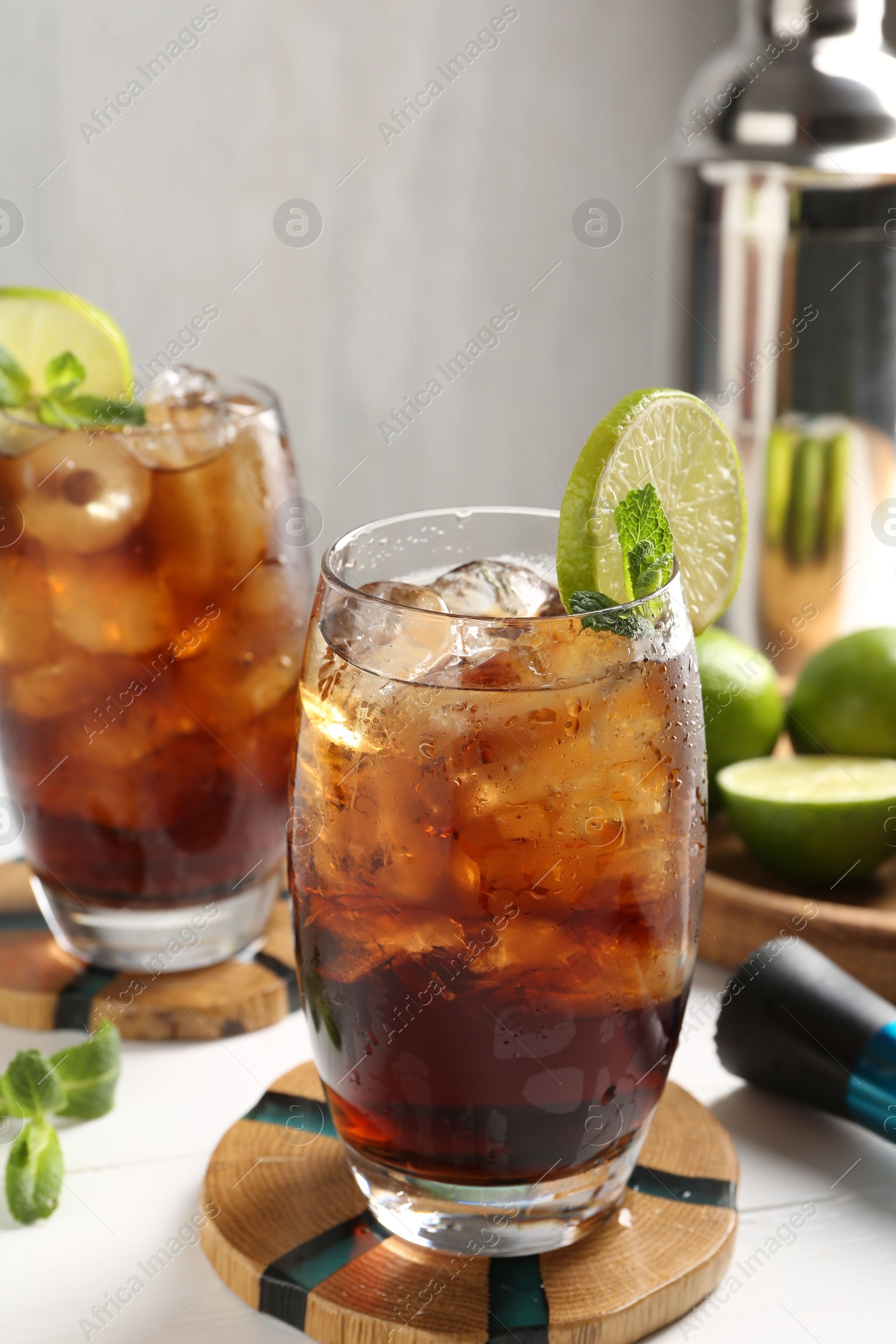 Tasty Cuba Libre cocktail in glasses, ingredients and muddler on white table, closeup Photo of Tasty Cuba Libre cocktail in glasses, ingredients and muddler on white table, closeup