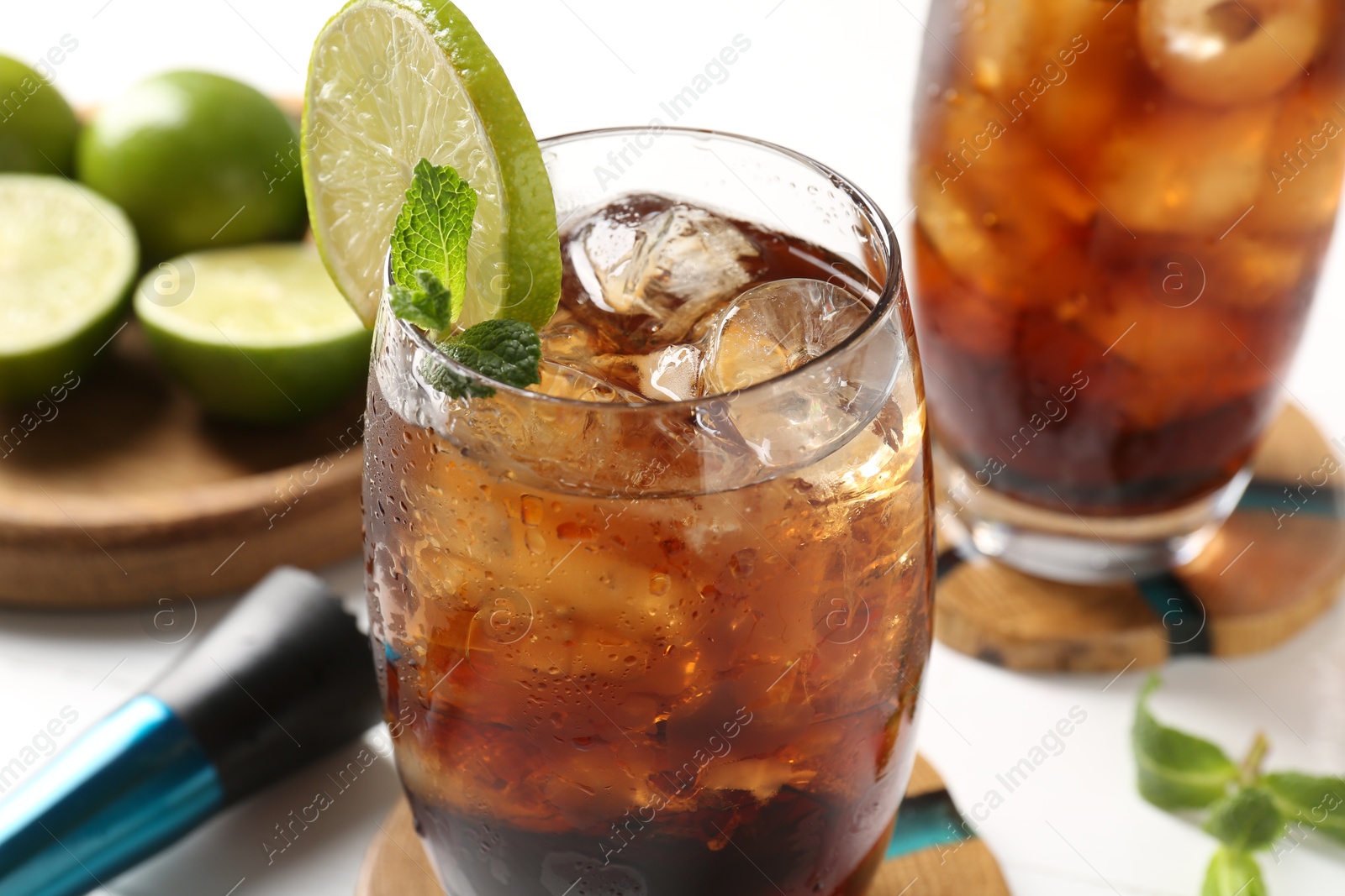 Tasty Cuba Libre cocktail in glasses, ingredients and muddler on white table, closeup Photo of Tasty Cuba Libre cocktail in glasses, ingredients and muddler on white table, closeup