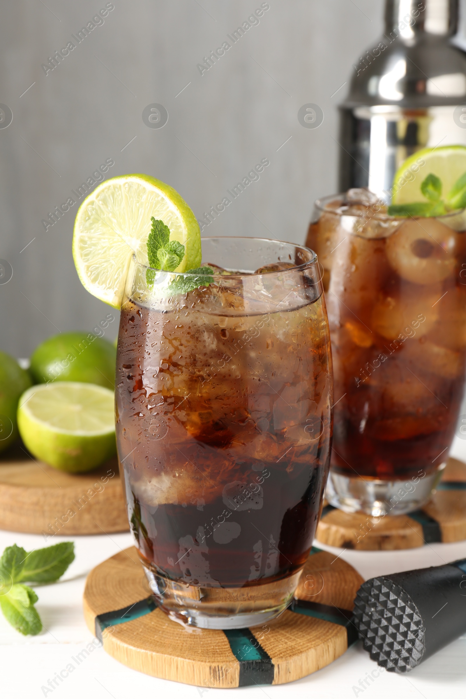 Tasty Cuba Libre cocktail in glasses, ingredients and muddler on white table, closeup Photo of Tasty Cuba Libre cocktail in glasses, ingredients and muddler on white table, closeup