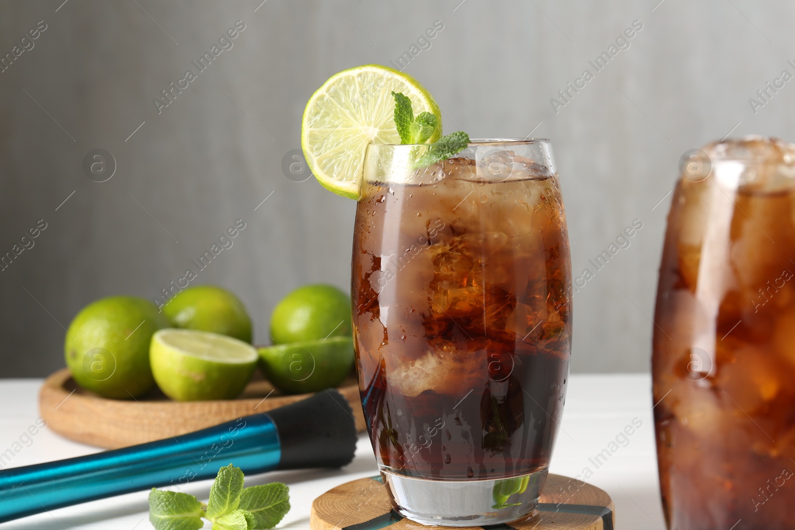 Tasty Cuba Libre cocktail in glasses, ingredients and muddler on white table, closeup Photo of Tasty Cuba Libre cocktail in glasses, ingredients and muddler on white table, closeup
