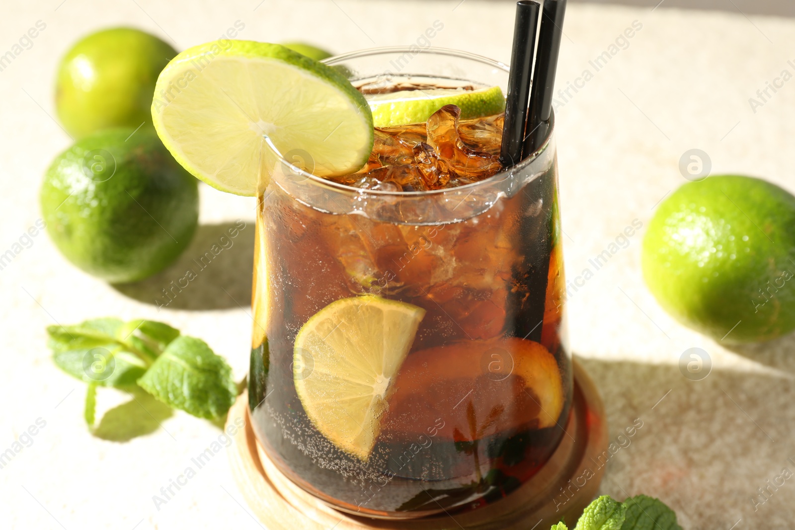 Tasty Cuba Libre cocktail in glass and ingredients on light textured table, closeup Photo of Tasty Cuba Libre cocktail in glass and ingredients on light textured table, closeup