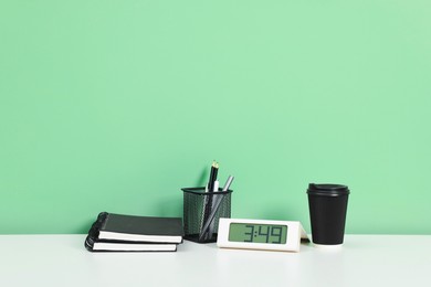 Photo of Stylish workplace with stationery and clock on white desk near light green wall. Space for text