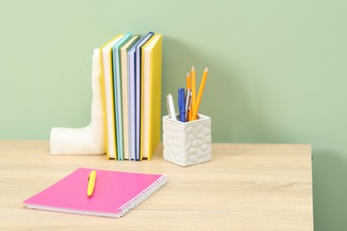 Photo of Stylish workplace with stationery on wooden desk near light green wall