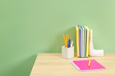 Photo of Stylish workplace with stationery on wooden desk near light green wall. Space for text