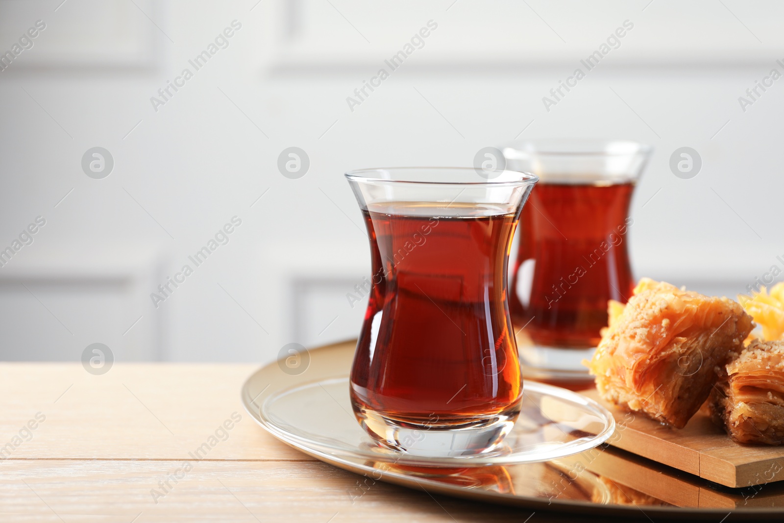 Tasty Turkish tea served with baklava on wooden table. Space for text Photo of Tasty Turkish tea served with baklava on wooden table. Space for text