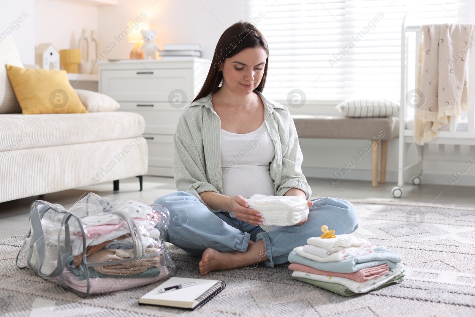Pregnant woman packing baby stuff to bring into maternity hospital at home Photo of Pregnant woman packing baby stuff to bring into maternity hospital at home