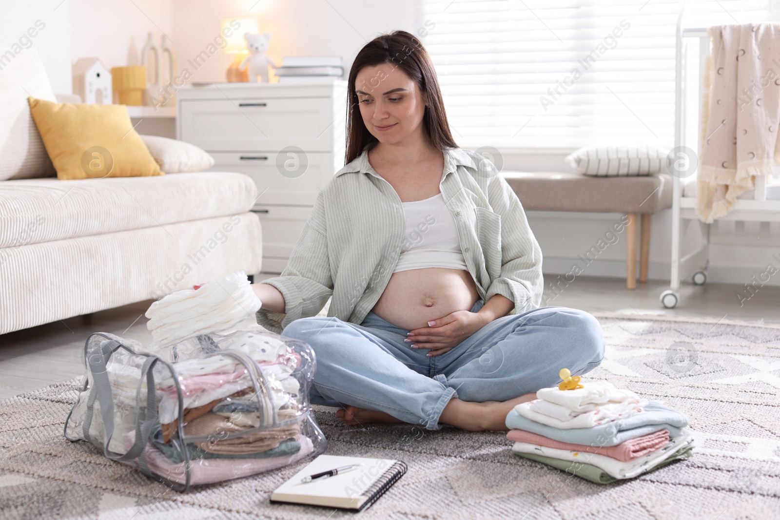 Pregnant woman packing baby stuff to bring into maternity hospital at home Photo of Pregnant woman packing baby stuff to bring into maternity hospital at home