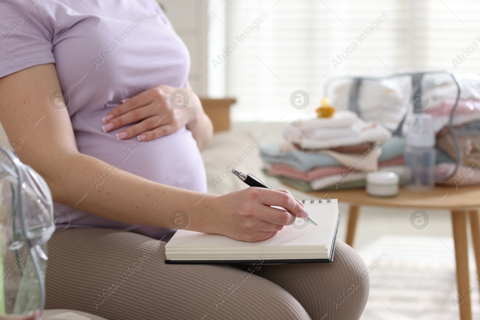 Pregnant woman preparing list of necessary items to bring into maternity hospital at home, closeup Photo of Pregnant woman preparing list of necessary items to bring into maternity hospital at home, closeup