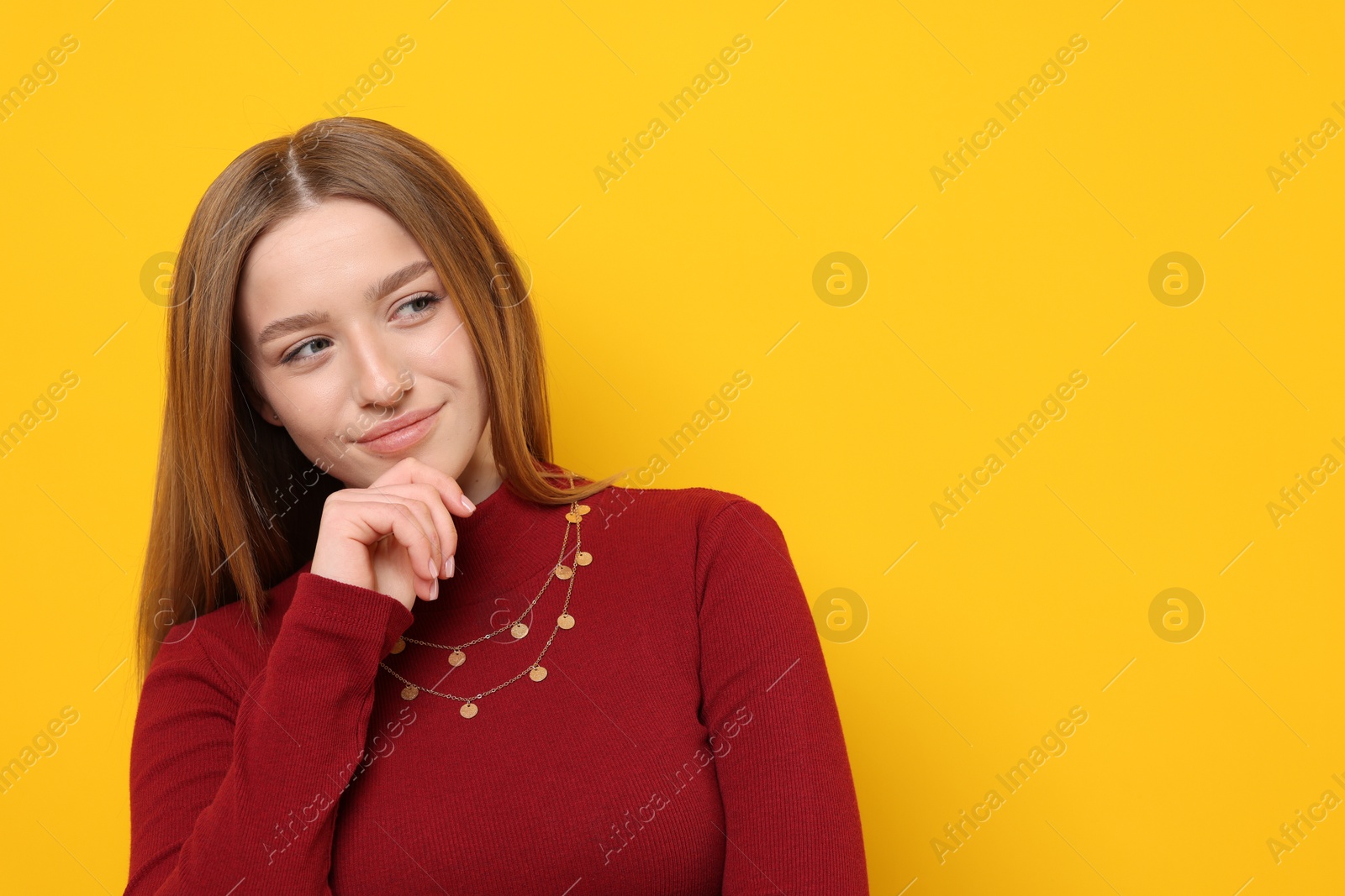 Photo of Portrait of thoughtful teenage girl on yellow background. Space for text