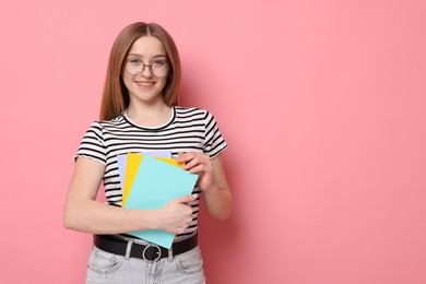 Photo of Portrait of smiling teenage girl with books on pink background. Space for text