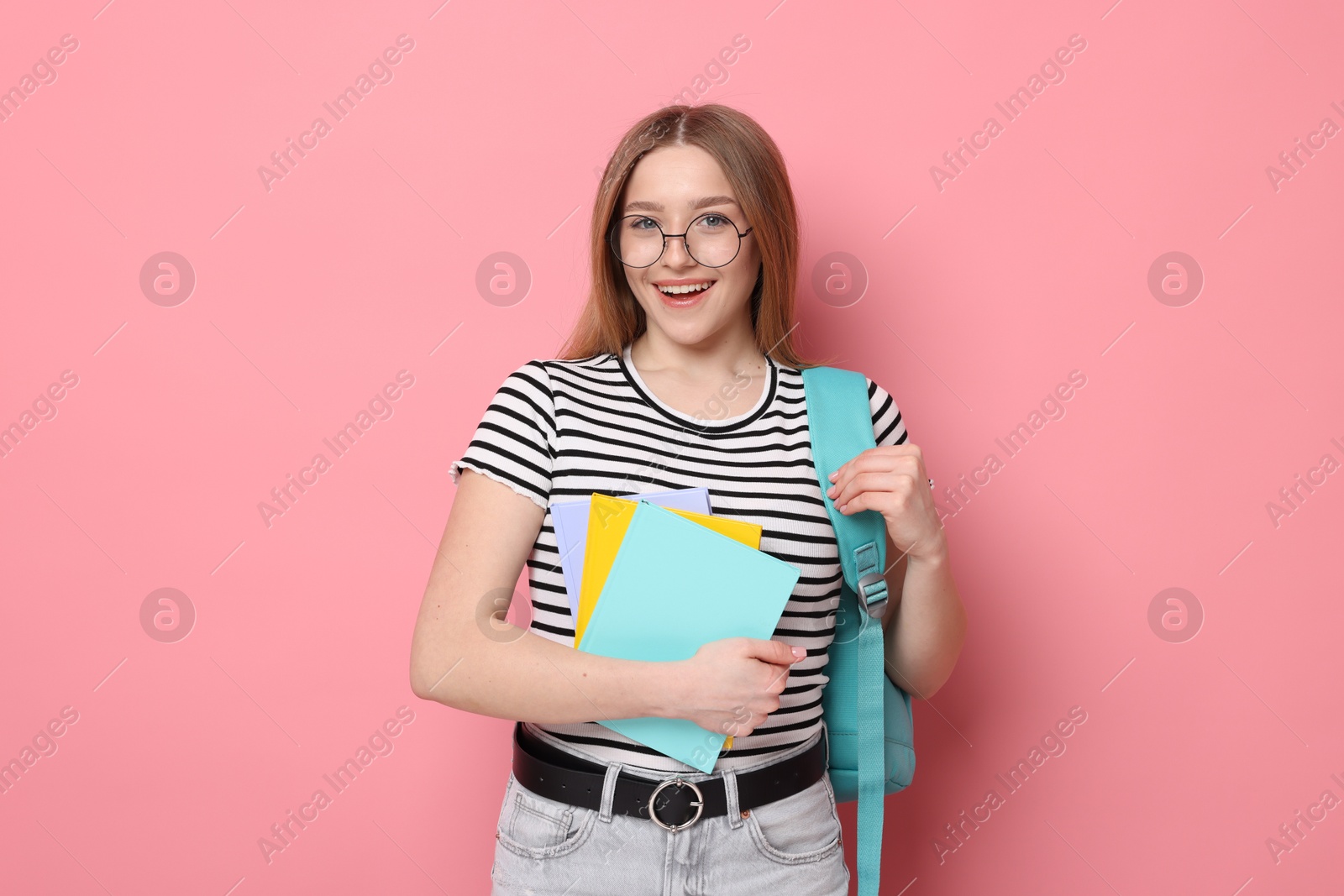 Portrait of happy teenage girl with books and backpack on pink background Photo of Portrait of happy teenage girl with books and backpack on pink background