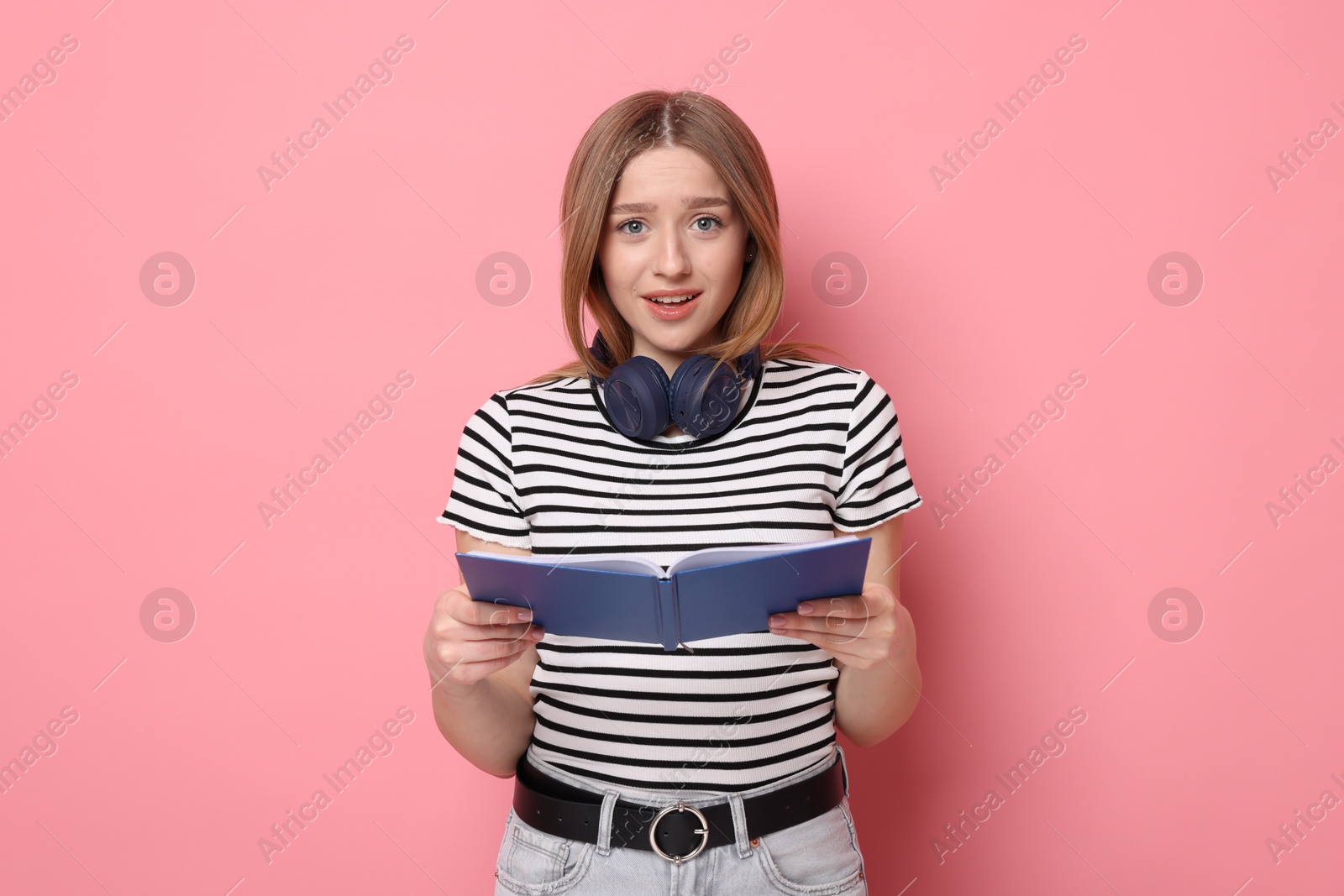 Emotional teenage girl with book on pink background Photo of Emotional teenage girl with book on pink background