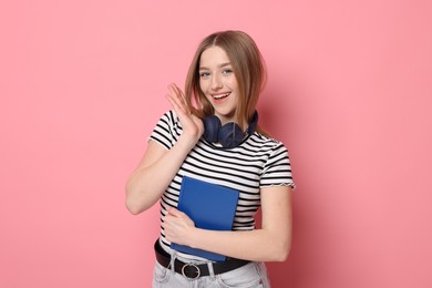 Photo of Portrait of smiling teenage girl with book on pink background