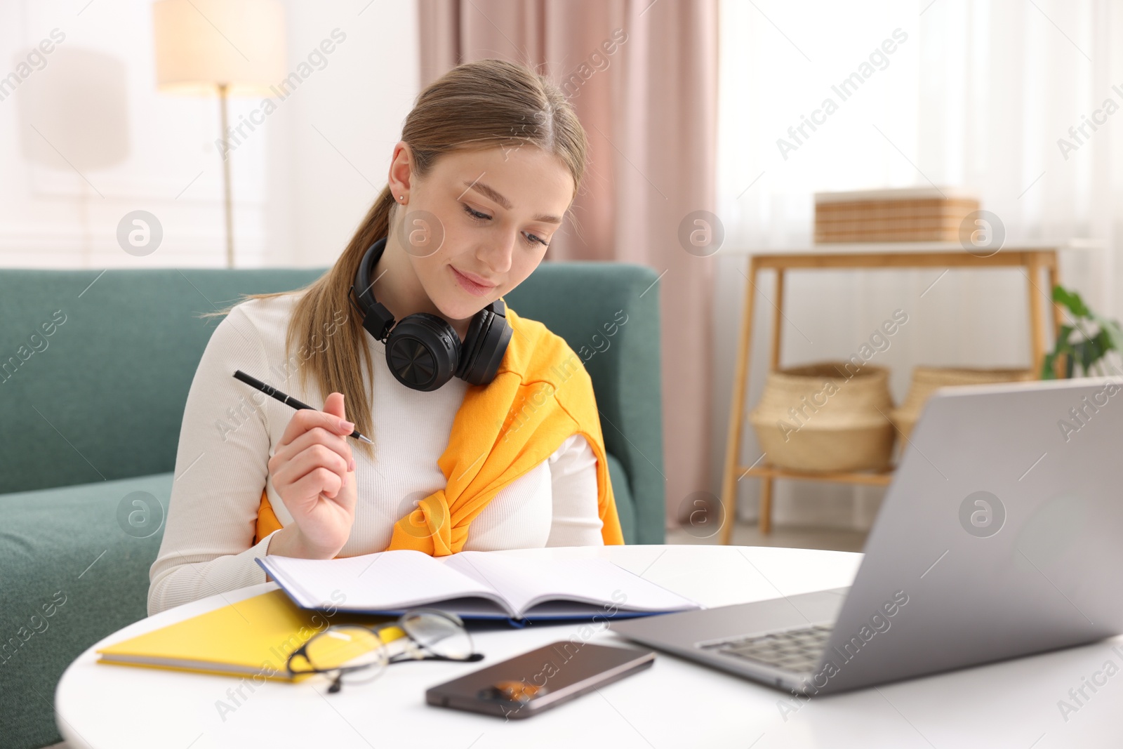 Teenage girl doing homework at table indoors Photo of Teenage girl doing homework at table indoors