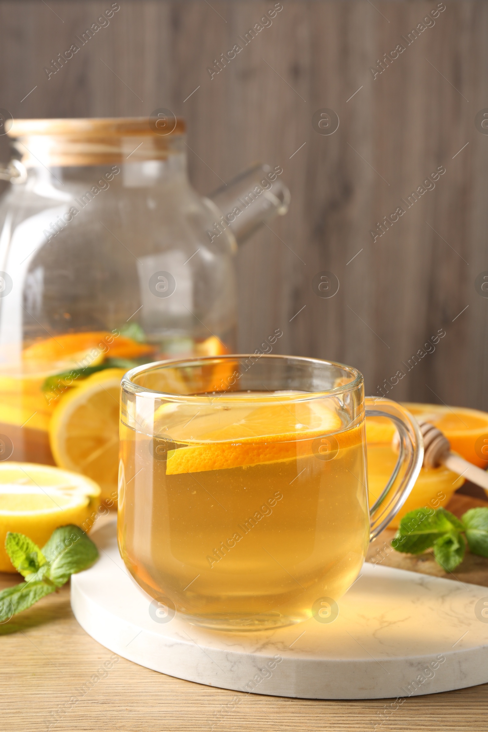 Aromatic fruit tea in glass cup, teapot, orange, lemon, honey and mint on wooden table, closeup Photo of Aromatic fruit tea in glass cup, teapot, orange, lemon, honey and mint on wooden table, closeup