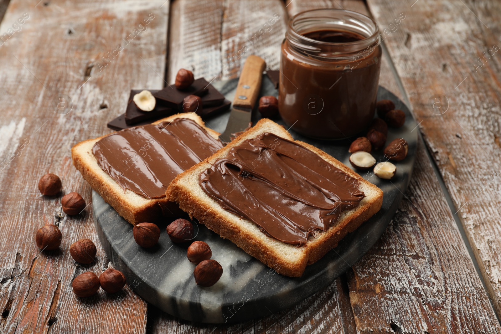 Toasts with tasty chocolate hazelnut spread and nuts on wooden table, closeup Photo of Toasts with tasty chocolate hazelnut spread and nuts on wooden table, closeup
