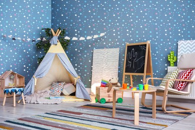 Image of Cozy playroom with toys, furniture and cute wallpaper. Stylish children's room interior