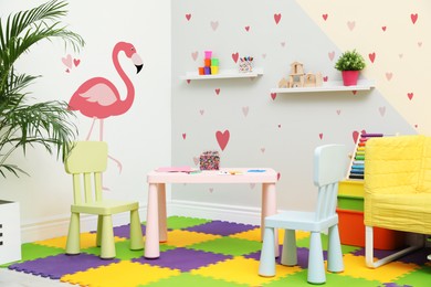 Image of Cozy playroom with toys, furniture and cute wallpaper. Stylish children's room interior