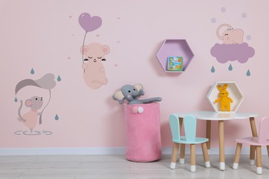 Image of Cozy playroom with toys, furniture and cute wallpaper. Stylish children's room interior