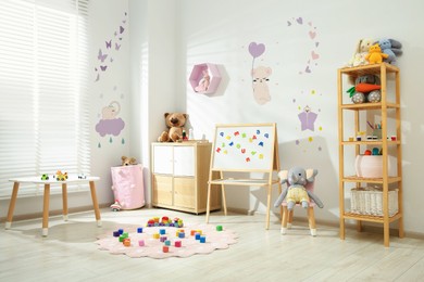 Image of Cozy playroom with toys, furniture and cute wallpaper. Stylish children's room interior