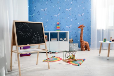 Image of Cozy playroom with toys, furniture and cute wallpaper. Stylish children's room interior