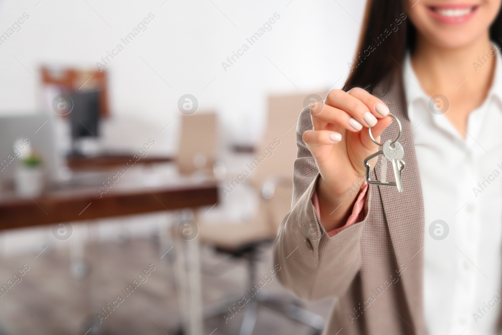 Real estate agent with house key in office, closeup. Space for text Image of Real estate agent with house key in office, closeup. Space for text