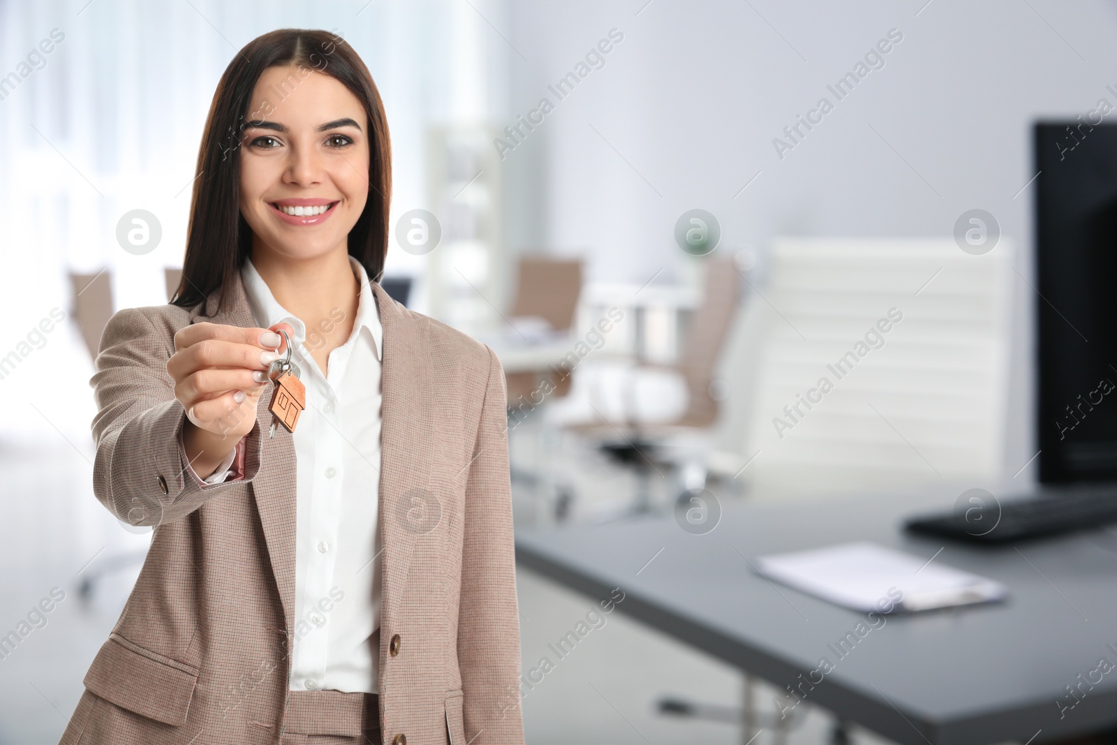 Real estate agent with house key in office, space for text Image of Real estate agent with house key in office, space for text