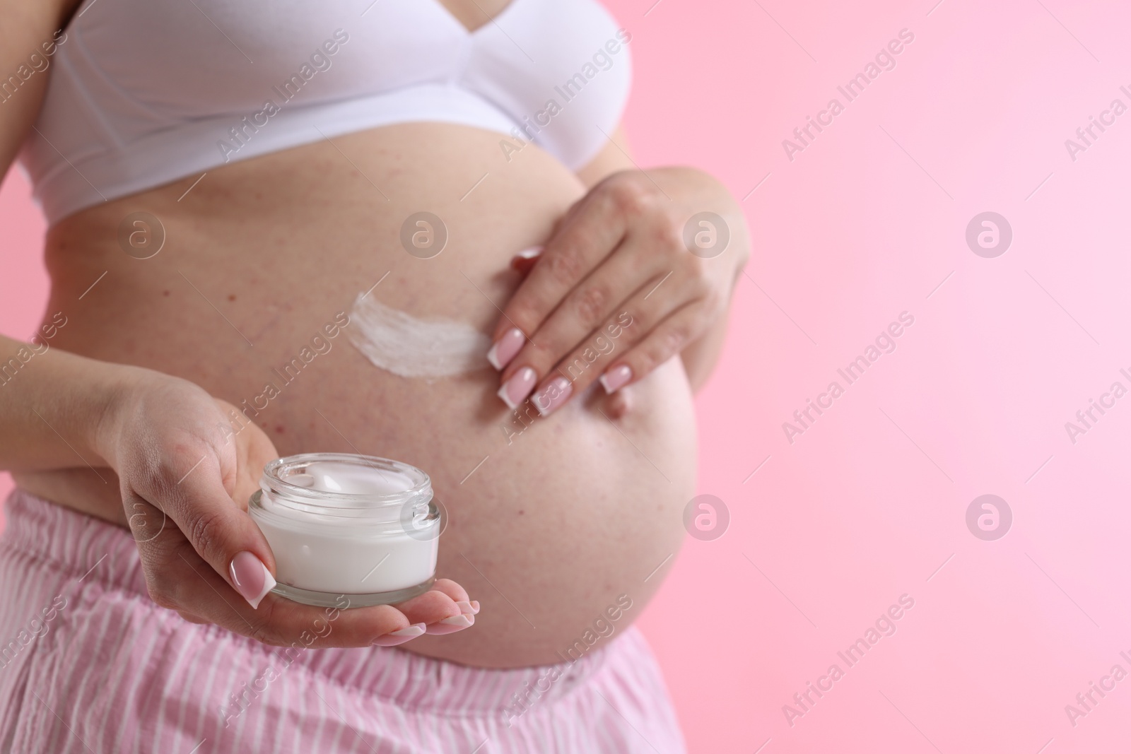 Pregnant woman with jar of cream on pink background, closeup. Space for text Photo of Pregnant woman with jar of cream on pink background, closeup. Space for text